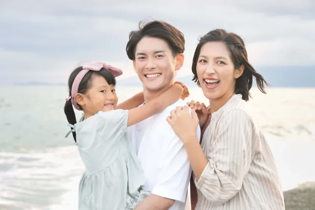 海岸で記念撮影をする夫婦と娘