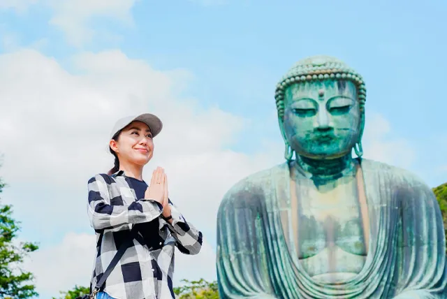 鎌倉の大仏の前で拝む女性