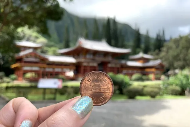 10円と平等院を見比べる女性