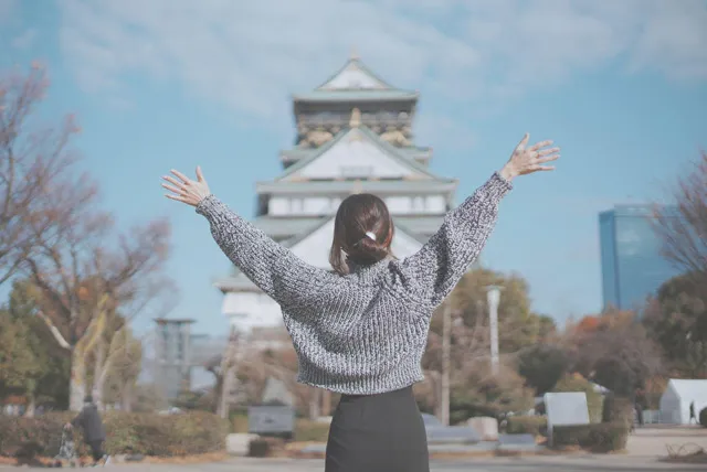 大阪城の前で万歳をする女性