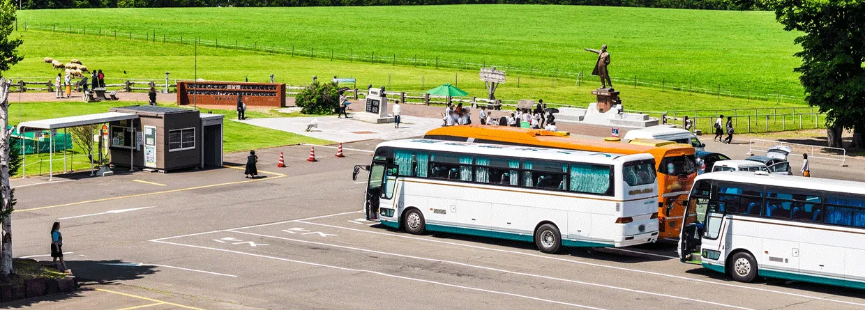 観光地の駐車場に停車する貸切バスと団体旅行のイメージ