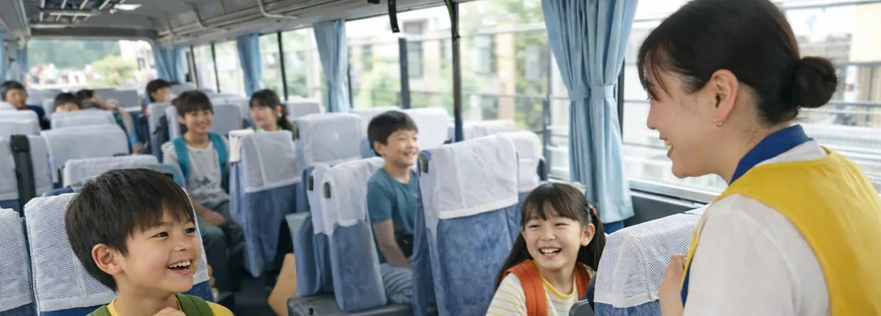 貸切バスの車内で会話を楽しむ子どもたちと引率者の様子