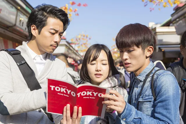 浅草で東京のガイドブックを開く3人の旅行者