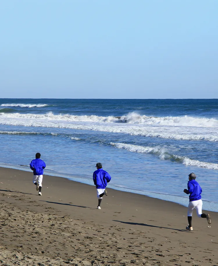 砂浜でジョギングをする野球部