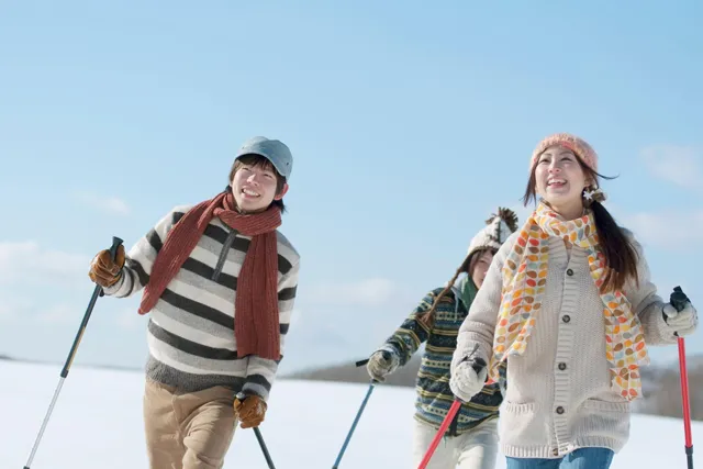 ストックを持って雪道を歩く3人組