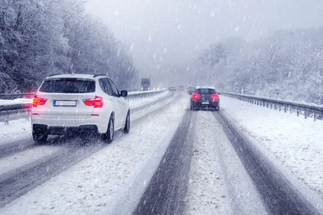 雪が降る高速道路を走る車